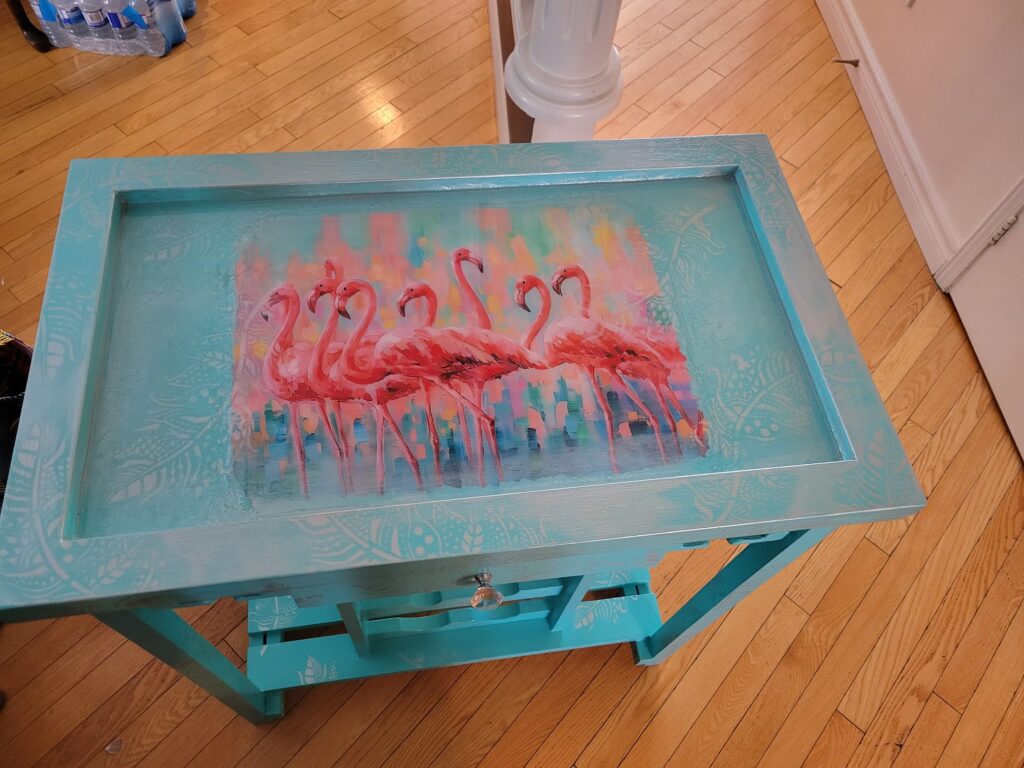 After: Refinished in a beautiful turquoise colour with a flamingo stencil. A new table top was added and silver leaf stencils adorn the bar cart. This was a custom order for a customer. Was sold for $450.00